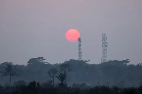 The sun setting behind a cell tower. Stock Photos