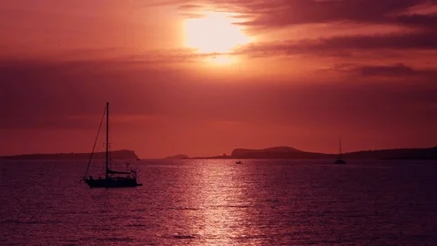Sun setting behind the clouds into Balearic sea with sailing ship Stock Footage 123086787