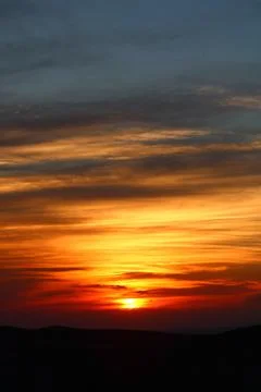 The sun setting behind the clouds. Orange sky. Amazing sunset Stock Photos