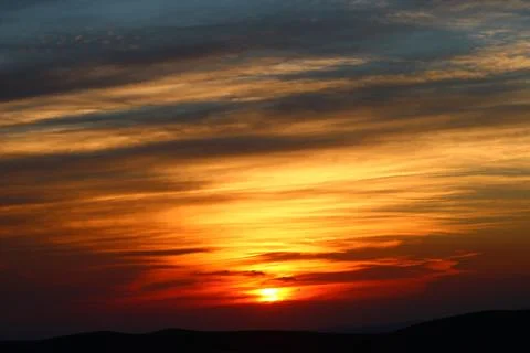 The sun setting behind the clouds. Orange sky. Amazing sunset Stock Photos