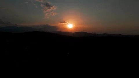 Sun Setting Behind Clouds Over Mountain Silhouette at Dusk Stock Footage 344440763