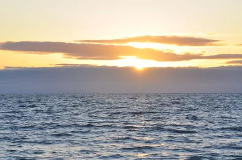 Sun setting behind clouds over the Pacific ocean Stock Photos