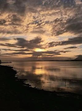 Sun setting behind clouds over a lagoon Stock Photos