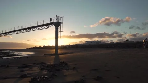 Sun setting behind lifeguard tower on empty beach Stock Footage 293082345
