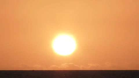 Sun Setting Behind Low Horizon Clouds Over Water Stock Footage 244678274