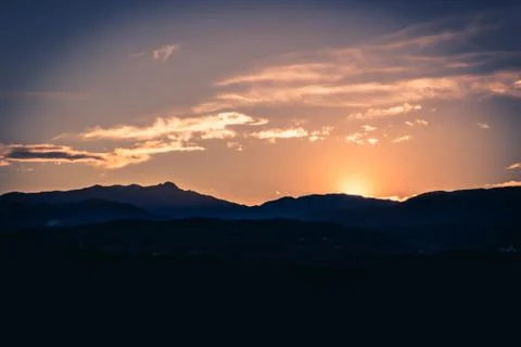 Sun setting behind a mountain Stock Photos