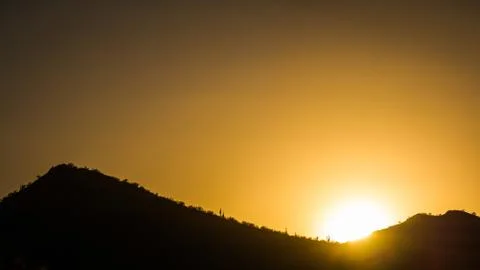 The Sun Setting Behind a Mountain Stock Photos