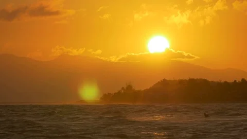Sun setting behind the mountain range, sea in the foreground Stock Footage 77559571
