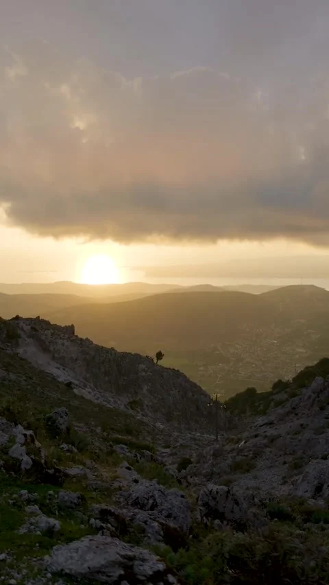 Sun setting behind a mountain range with the sea in the background Stock Footage 294964005