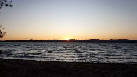Sun setting behind the mountains in the distance over the lake Stock Footage 211065685