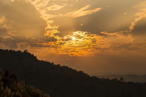 The sun is setting behind the mountains. Stock Photos
