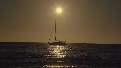 Sun setting behind a sailing boat at the sea Stock-Footage 122862623