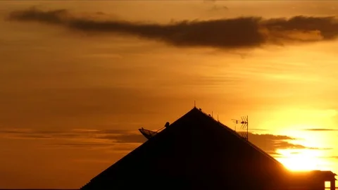Sun setting behind a silhouetted building House, bird standing roof, 스톡 동영상 81367824