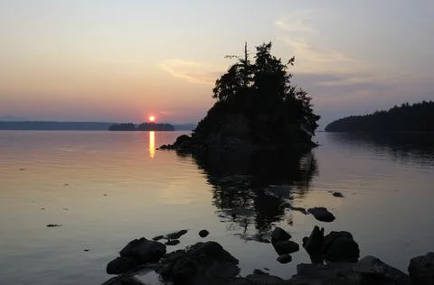 Sun setting behind a small islet in Princess Bay, Wallace Island, Gulf Island Stock Photos