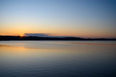 Sun setting behind some clouds over the lake Stock Photos
