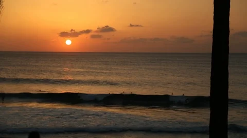 The Sun Setting Behind Surfers Surfing in Hawaii Stock Footage 91222274