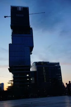 Sun setting behind tall building with unique architectural cubic design Stock-Fotos