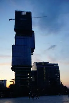Sun setting behind tall building with unique architectural cubic design 스톡 사진