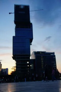 Sun setting behind tall building with unique architectural cubic design Stock Photos