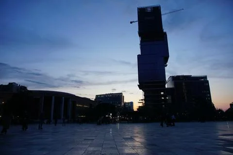 Sun setting behind tall building with unique architectural cubic design Stock-Fotos