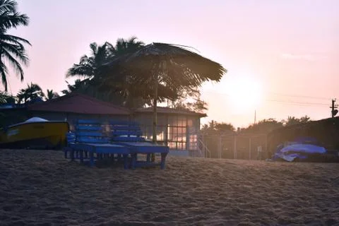 Sun setting behind the trees with two blue chair on a beach in Goa Stock Photos