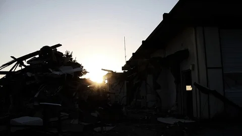 Sun setting between trash pile and building Stock Footage 95115183