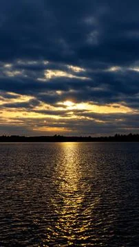 The sun is setting, casting a warm glow on the water Stock Photos