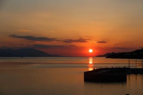 Sun setting down over the sea, The red disc of the sun touches the horizon Stock Photos