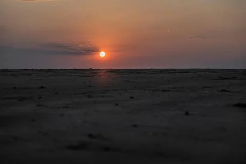 Sun Setting on the Horizon Behind a Sandy Beach Hill Stock Photos