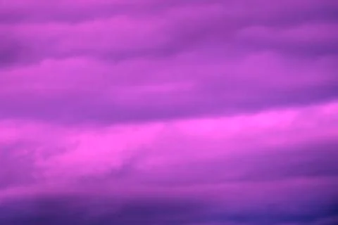 The sun setting to the left lights the sky in pastel shades of pink, blue and Stock Photos