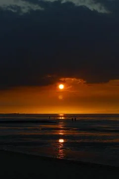 Sun setting on ocean creating light reflections with dark cloud cover and p.. Stock Photos