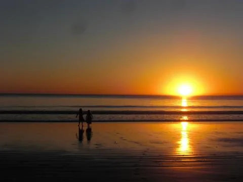 Sun setting in the open ocean, two kids watching Stock Photos