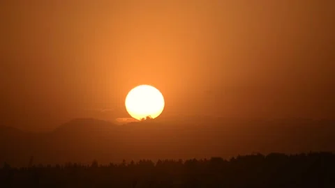 Sun setting in orange sky. Big bright yellow sun moves down Stock Footage 156402443