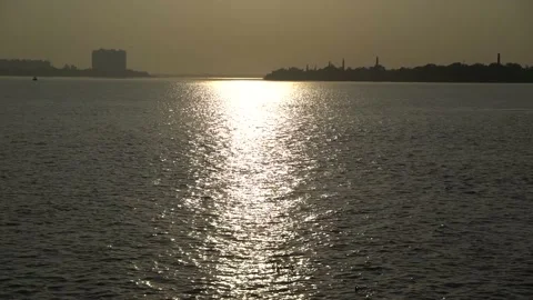 The sun is setting on the other side of the river where civilization has develop Stock Footage 222497441