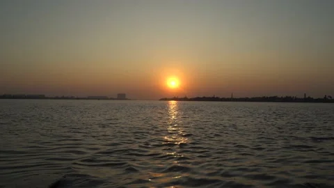 The sun is setting on the other side of the river where civilization has develop Video stock 222766679