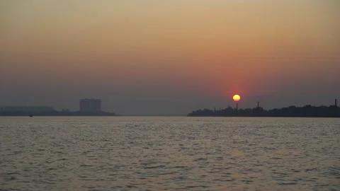 The sun is setting on the other side of the river where civilization has develop Stock Footage 222766795