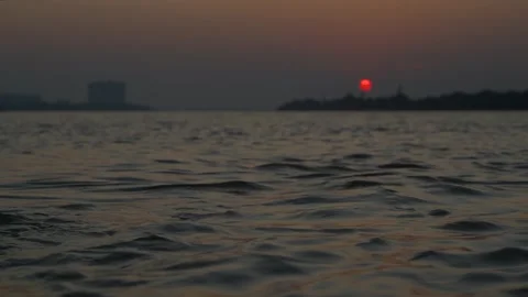 The sun is setting on the other side of the river where civilization has develop Video stock 222766935