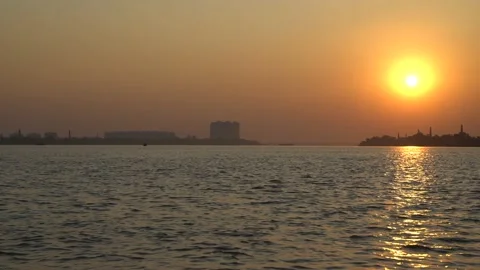 The sun is setting on the other side of the river where civilization has develop Stock Footage 222767120