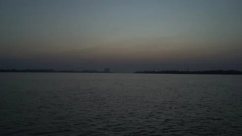 The sun is setting on the other side of the river where civilization has develop Video stock 223822840