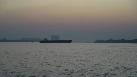 The sun is setting on the other side of the river where civilization has develop Video stock 223823324