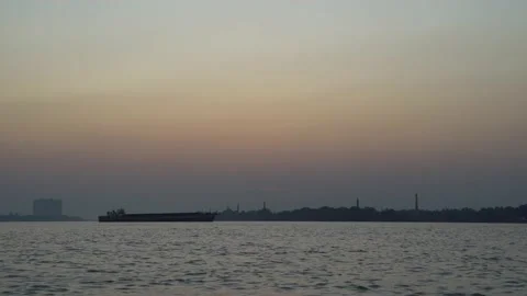 The sun is setting on the other side of the river where civilization has develop Stock Footage 223823983