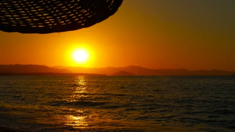 Sun setting over a calm ocean with mountains in the distance Stock Footage 302822562