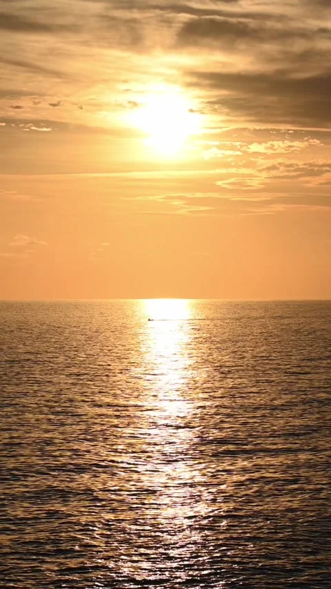Sun setting over calm sea with golden reflection on water Видео 345079969