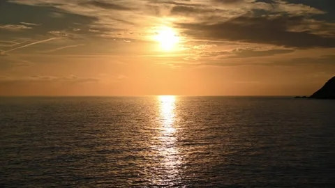 Sun setting over calm sea with golden reflection on water Видео 345080059
