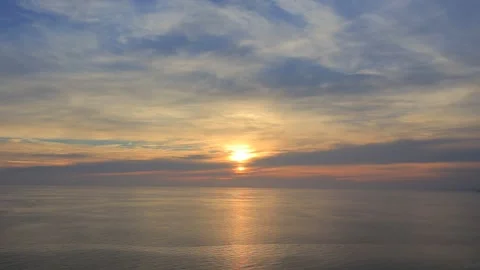 Sun setting over calm sea horizon under a cloudy sky Stock Footage 347104548