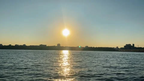 Sun setting over a cityscape reflected on water surface Stock Footage 306580172