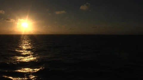 Sun setting over dark ocen from moving ship (sun on left) Video stock 90499532