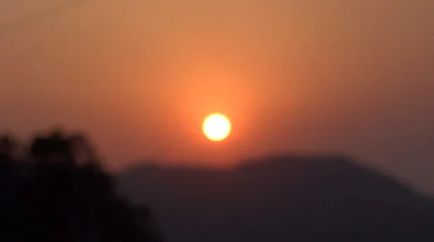 Sun is setting over a distant range of hills in a rural setting (closeup) Stock-Footage 38117179