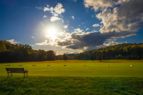 Sun setting over golf course with inviting bench Fotos Stock