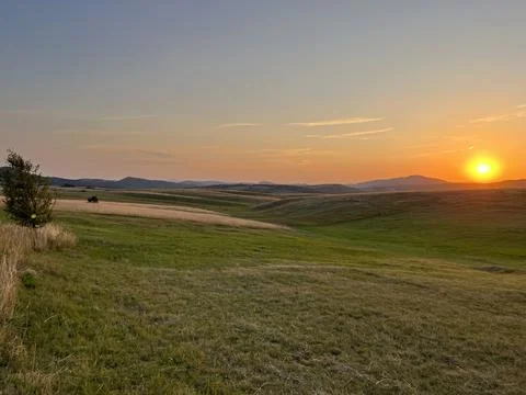 Sun Setting Over Hills and Field, Dramatic Orange Sky Fotos Stock